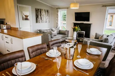 a living room with a wooden table and chairs at Ream Hills Holiday Park in Blackpool