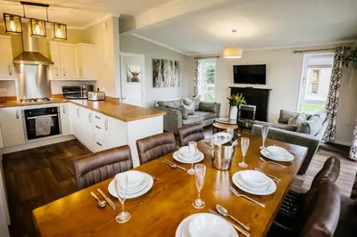a kitchen and living room with a wooden table and chairs at Ream Hills Holiday Park in Blackpool