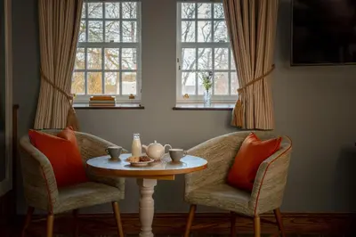 a room with two chairs and a table and two windows at The Royal Heysham in Heysham