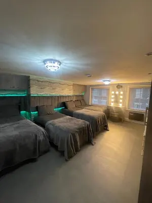 a room with three beds and a chandelier at 19 Rodney Street Apartments in Liverpool