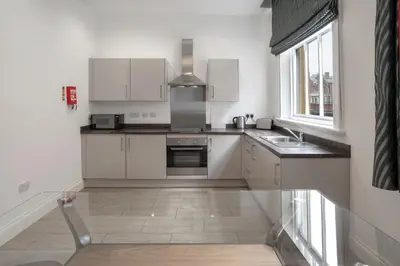 a kitchen with white cabinets and a sink and a window at The Castle Collection - 25 Castle Street in Liverpool