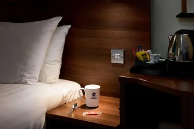 a coffee cup on a wooden table next to a bed at Best Western Carlton Hotel in Blackpool