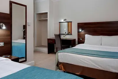a hotel room with two beds and a desk and a mirror at Best Western Carlton Hotel in Blackpool