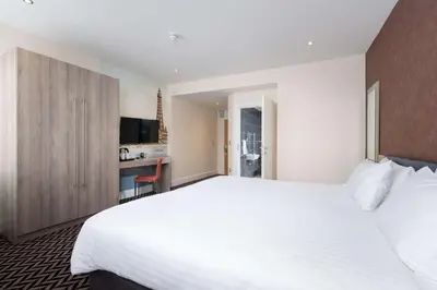 a bedroom with a large white bed and a kitchen at Best Western Carlton Hotel in Blackpool