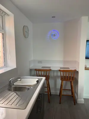 a kitchen with a sink and two wooden stools at San Remo Apartments Blackpool in Blackpool