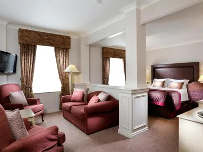 a hotel room with a bed and a couch and a chair at Macdonald Kilhey Court Hotel in Wigan
