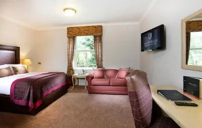 a hotel room with a bed and a couch and a desk at Macdonald Kilhey Court Hotel in Wigan