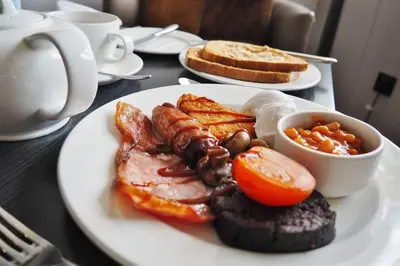a plate of breakfast food with bacon eggs and toast at Macdonald Kilhey Court Hotel in Wigan