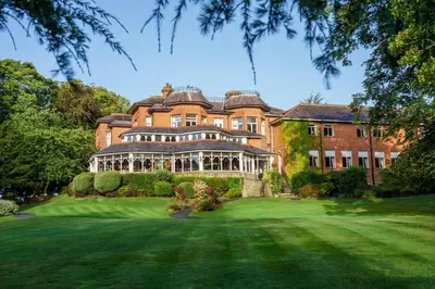 a large brick house with a green yard at Macdonald Kilhey Court Hotel in Wigan