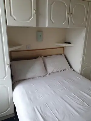 a bed in a small room with white cabinets at Manhattan Lodge in Lytham St Annes