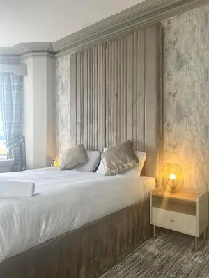 a bedroom with a bed and a table with a lamp at The Commodore Inn in Grange Over Sands