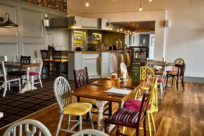 a restaurant with tables and chairs and a kitchen at The Commodore Inn in Grange Over Sands