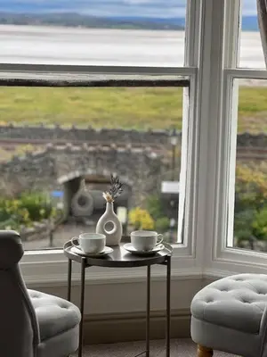a table with two cups and a vase on it next to a window at The Commodore Inn in Grange Over Sands