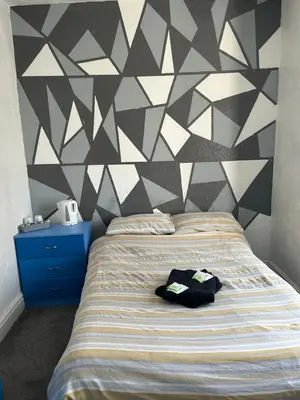 a bedroom with a bed with a geometric wall at The Beckwood Hotel in Blackpool