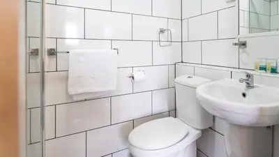 a white bathroom with a toilet and a sink at Trivelles Seaforth in Bootle