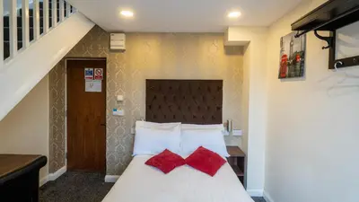 a bedroom with a bed with two red pillows at Trivelles Seaforth in Bootle