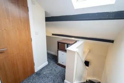 an attic room with a staircase and a wooden door at Trivelles Seaforth in Bootle