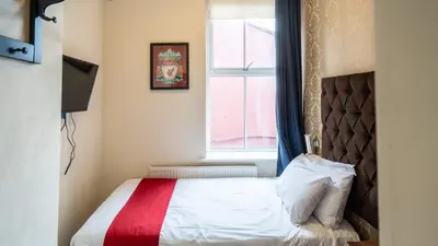 a small bedroom with a bed with a window at Trivelles Seaforth in Bootle
