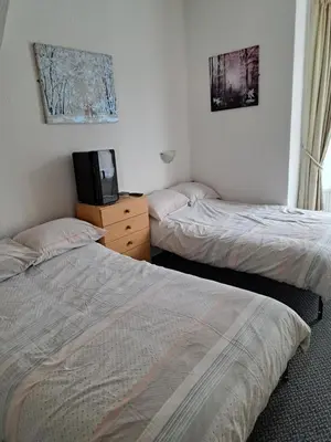 two beds in a room with a tv on a dresser at Montgomery Hotel in Blackpool