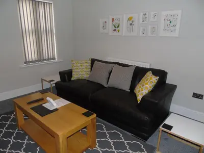 a living room with a black couch and a coffee table at Jeffersons Hotel & Serviced Apartments - The Steel Works in Barrow in Furness