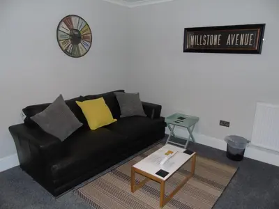 a black leather couch in a living room with a coffee table at Jeffersons Hotel & Serviced Apartments - The Steel Works in Barrow in Furness