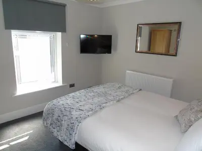 a white bedroom with a bed and a mirror at Jeffersons Hotel & Serviced Apartments - The Steel Works in Barrow in Furness