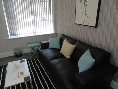 a living room with a black leather couch and a table at Jeffersons Hotel & Serviced Apartments - The Steel Works in Barrow in Furness