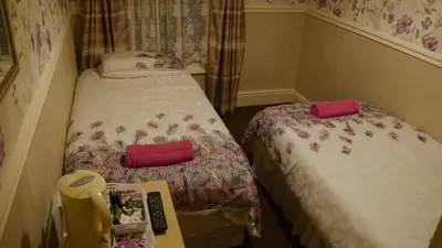 a small room with two beds and a desk at Hornby House Hotel in Blackpool