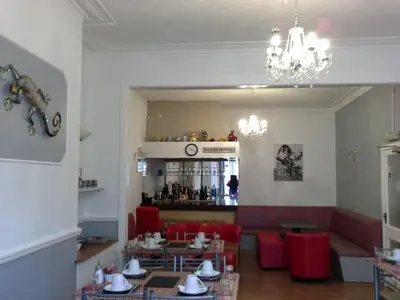 a restaurant with tables and red chairs and a bar at Hornby House Hotel in Blackpool