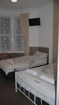two beds in a room with a tv on the wall at Hornby House Hotel in Blackpool