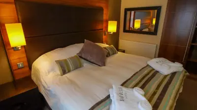 a bed in a hotel room with towels on it at The Big Blue Hotel - Blackpool Pleasure Beach in Blackpool