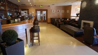 a restaurant with a bar with chairs and a fireplace at The Big Blue Hotel - Blackpool Pleasure Beach in Blackpool