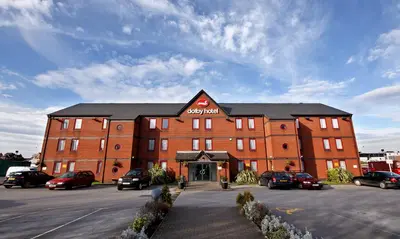 a large brick building with cars parked in a parking lot at The Dolby Hotel Liverpool - Free city centre parking in Liverpool