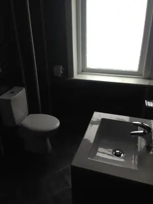 a bathroom with a toilet and a sink and a window at Yado Hotel in Blackpool