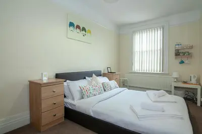 a bedroom with a large white bed with a wooden dresser at The Jollys in Bootle