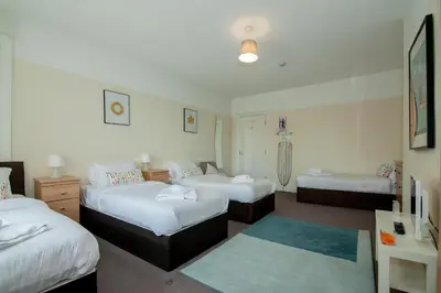 a hotel room with three beds and a table at The Jollys in Bootle
