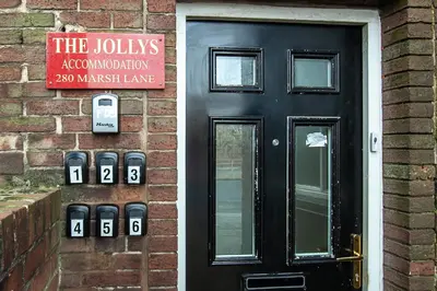 a black door with parking meters next to a brick building at The Jollys in Bootle