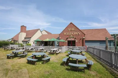 a group of picnic tables in front of a building at Willows, Blackburn by Marston's Inn in Blackburn