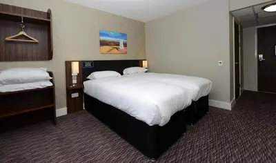 a hotel room with a large bed with white sheets at Willows, Blackburn by Marston's Inn in Blackburn