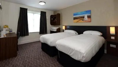 a hotel room with two beds and a window at Willows, Blackburn by Marston's Inn in Blackburn