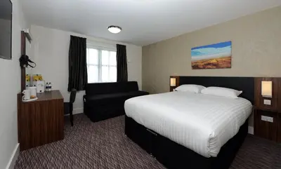 a hotel room with a bed and a chair at Willows, Blackburn by Marston's Inn in Blackburn