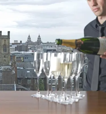 a man is pouring champagne into wine glasses on a table at Hope Street Hotel in Liverpool
