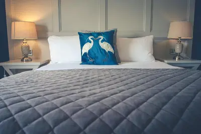 a bedroom with a bed with a blue pillow and two lamps at Shard Riverside in Poulton le Fylde