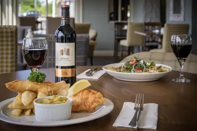 a table with a plate of food and a bottle of wine at Shard Riverside in Poulton le Fylde