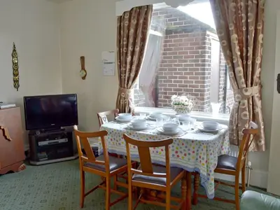 a dining room table with chairs and a table and a television at Marstan House in Standish