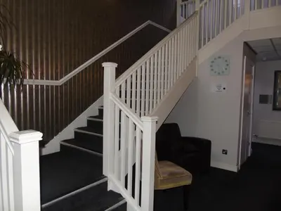 a staircase with a white rail and a chair at The Avenue Hotel Ltd in Clitheroe