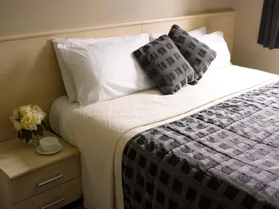 a bed with pillows and a vase of flowers on a table at The Avenue Hotel Ltd in Clitheroe