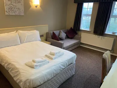 a bedroom with a white bed and a couch at The Avenue Hotel Ltd in Clitheroe