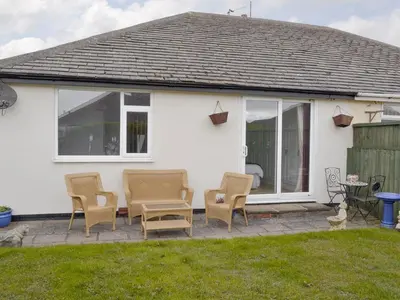 a patio with chairs and a table in front of a house at Rossall Beach Cottage in Cleveleys