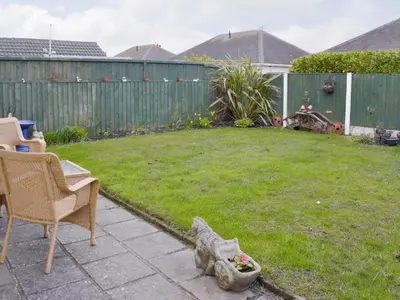 a backyard with a chair and a yard with a fence at Rossall Beach Cottage in Cleveleys
